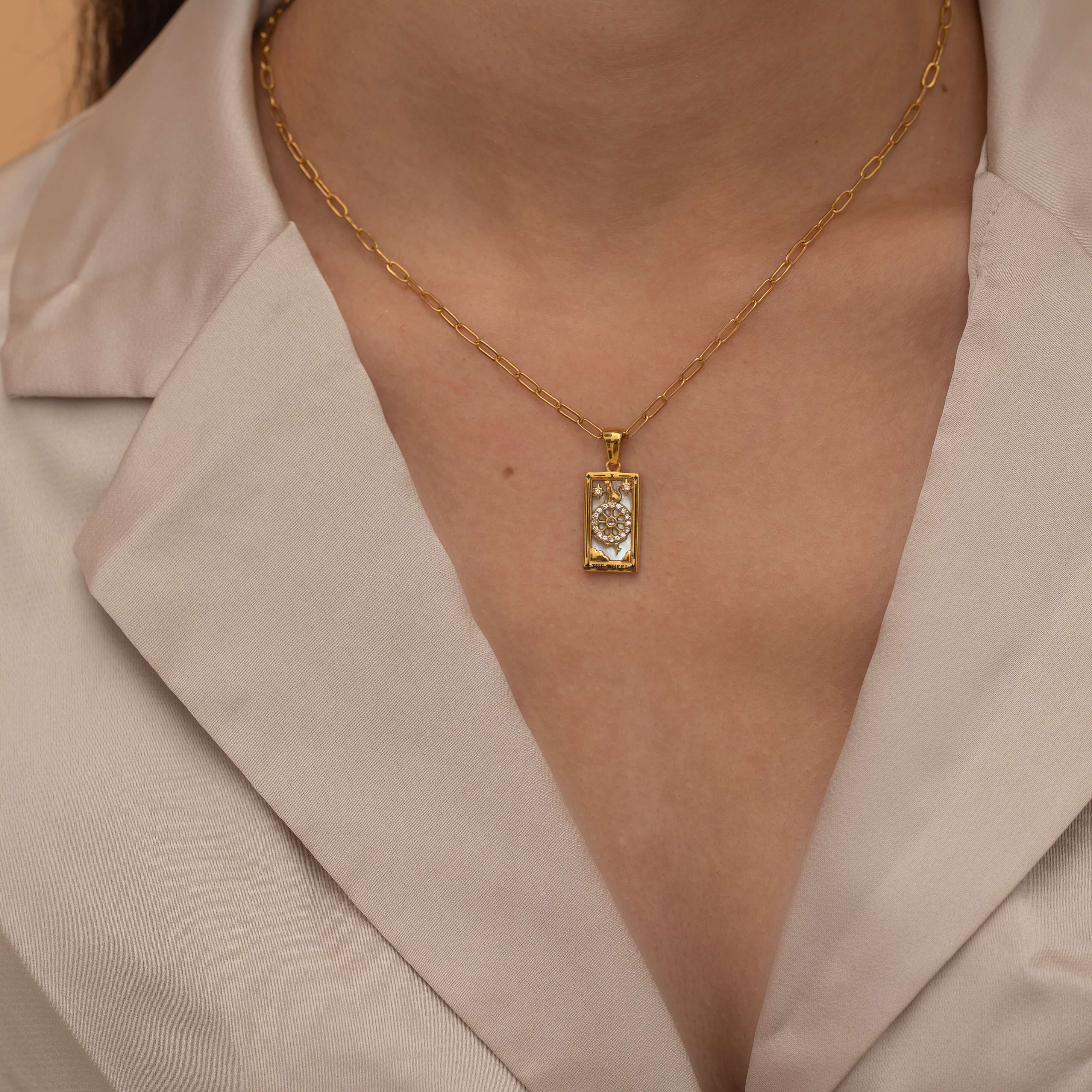 Gold the wheel tarot necklace with cubic zirconia accents and a mother of pearl back stone, symbolizing change, destiny, and the cycles of life. 