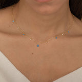 Dainty sterling silver and 14k gold plated necklace featuring four square blue zircon stones, one centered teardrop-shaped blue zircon stone, and four white cubic zirconia accents between the December birthstones.