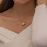 Gold U-shaped necklace with a single pearl centerpiece in the middle, creating a minimalist and elegant jewelry design.