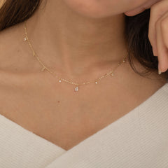 
Dainty sterling silver and 14k gold plated necklace featuring four square diamond-colored cubic zirconia stones, one centered teardrop-shaped diamond stone, and four white cubic zirconia accents between the diamond. 