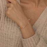 Close-up of a dainty pearl charm bracelet on a wrist