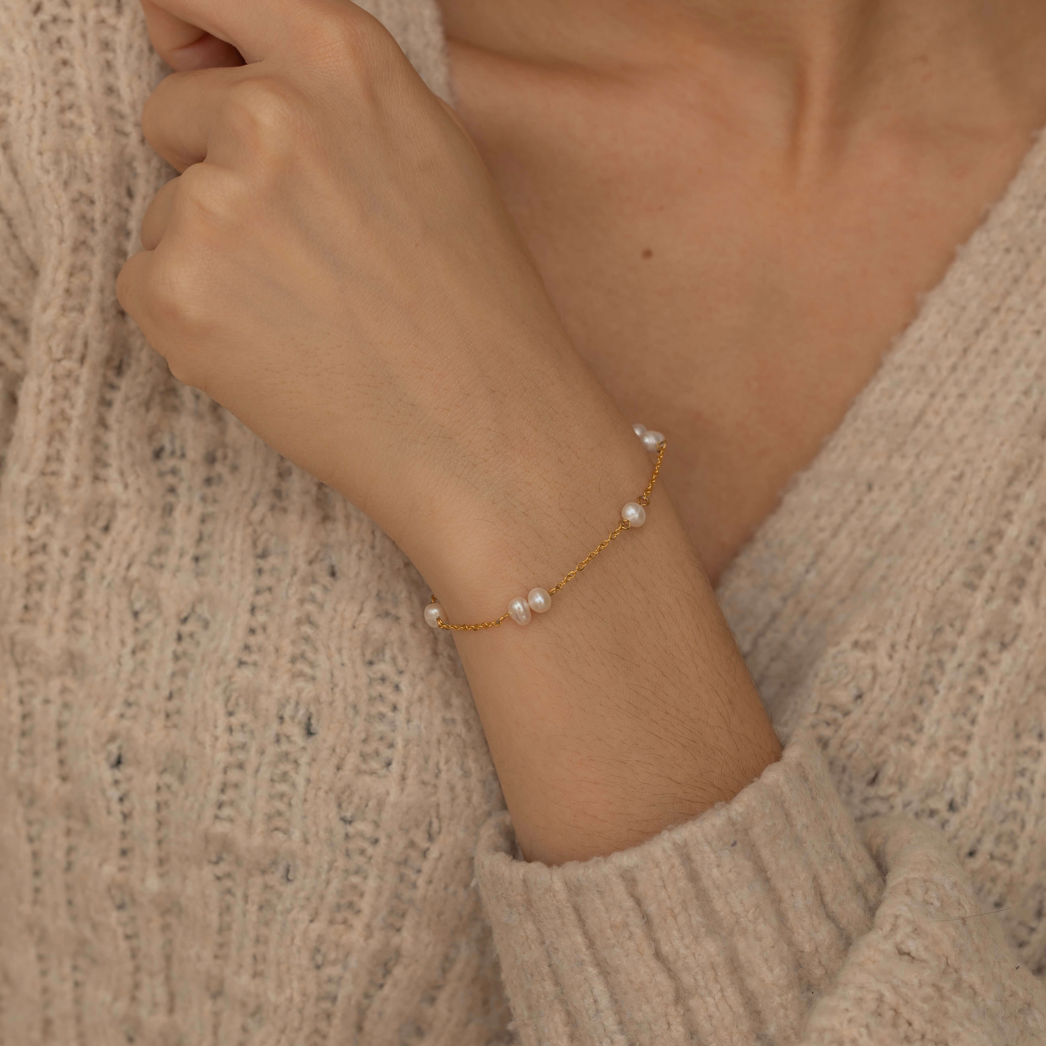 Close-up of a dainty pearl charm bracelet on a wrist