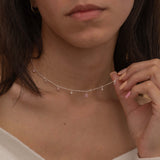 Dainty sterling silver necklace featuring four square pink-colored cubic zirconia stones, one centered teardrop-shaped pink stone, and four white cubic zirconia accents between the pink birthstones. 