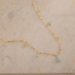 Dainty sterling silver and 14k gold plated necklace featuring four square opal birthstone stones, one centered teardrop-shaped opal stone, and four white cubic zirconia accents between the opal birthstones. Perfect for mother’s day and prom. 