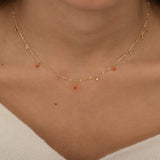 
Dainty sterling silver and 14k gold plated necklace featuring four square orange-colored cubic zirconia stones, one centered teardrop-shaped orange stone, and four white cubic zirconia accents between the orange birthstones. 
