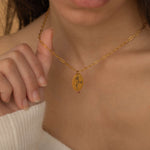 Up-close view of a gold personalized birth flower necklace engraved, worn by a woman.