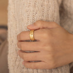 Gold ring with bold ridged design on a woman's hand