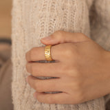 Gold ring with bold ridged design on a woman's hand