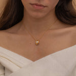 Gold U-shaped necklace with a single pearl centerpiece in the middle, creating a minimalist and elegant jewelry design.