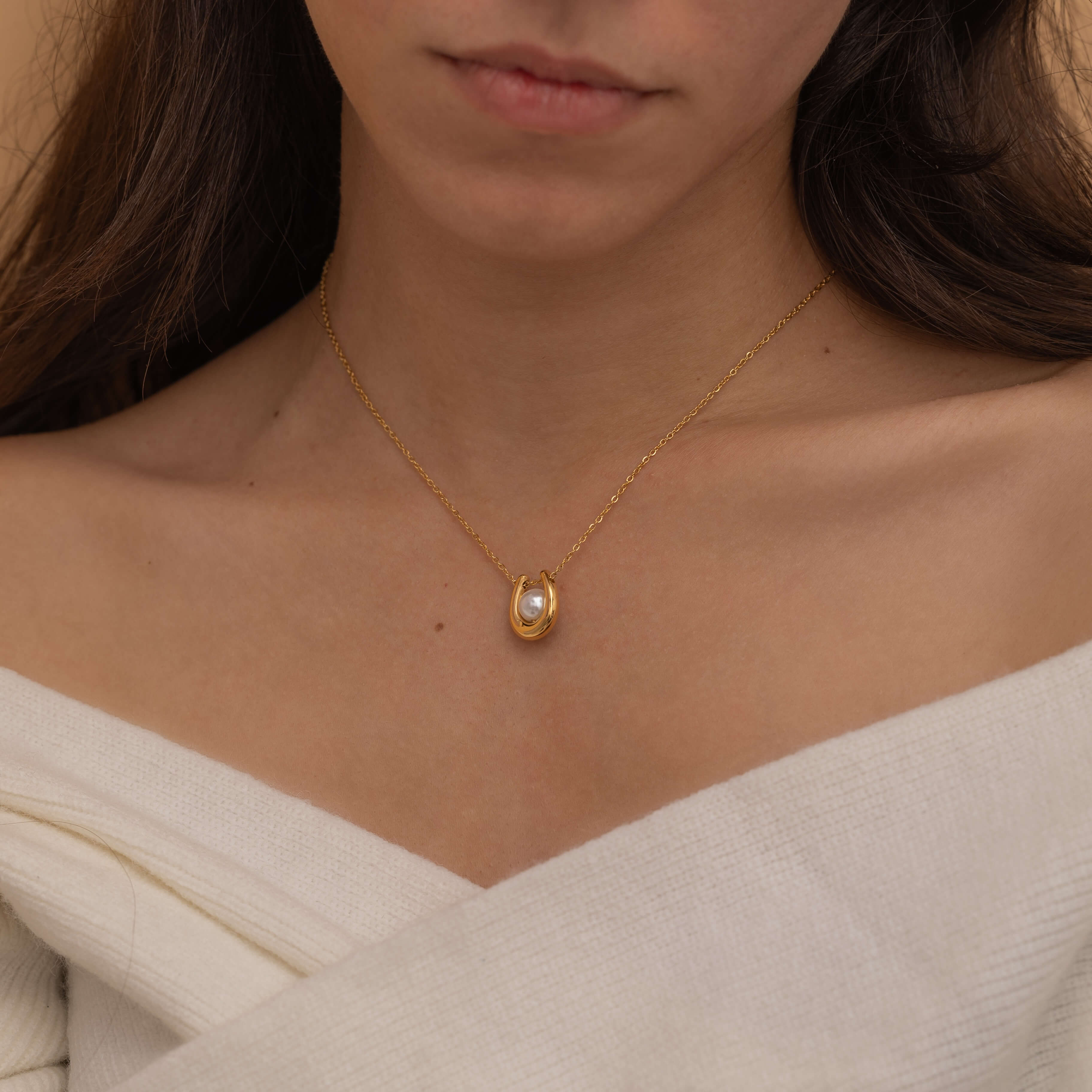 Gold U-shaped necklace with a single pearl centerpiece in the middle, creating a minimalist and elegant jewelry design.