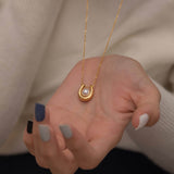 Gold U-shaped necklace with a single pearl centerpiece in the middle, creating a minimalist and elegant jewelry design.