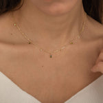 Dainty sterling silver and 14k gold plated necklace featuring four square peridot-colored cubic zirconia stones, one centered teardrop-shaped peridot stone, and four white cubic zirconia accents between the peridot.