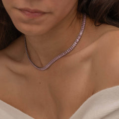 Elegant silver tennis necklace with a continuous row of sparkling, rectangular-cut stones. Perfectly aligned pink gemstones create a seamless shimmer, adding timeless sophistication to any look. Classic luxury jewelry piece ideal for formal occasions or adding everyday elegance.