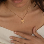 Close-up of a constellation necklace pendant worn by a woman, showcasing a minimalist engraved star pattern.