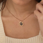 Close-up of a rose gold pendant necklace featuring an engraved dog nose print design worn by a woman.