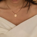 close up of a rose gold hand gesture necklace worn by a women showcasing a peace sign.
