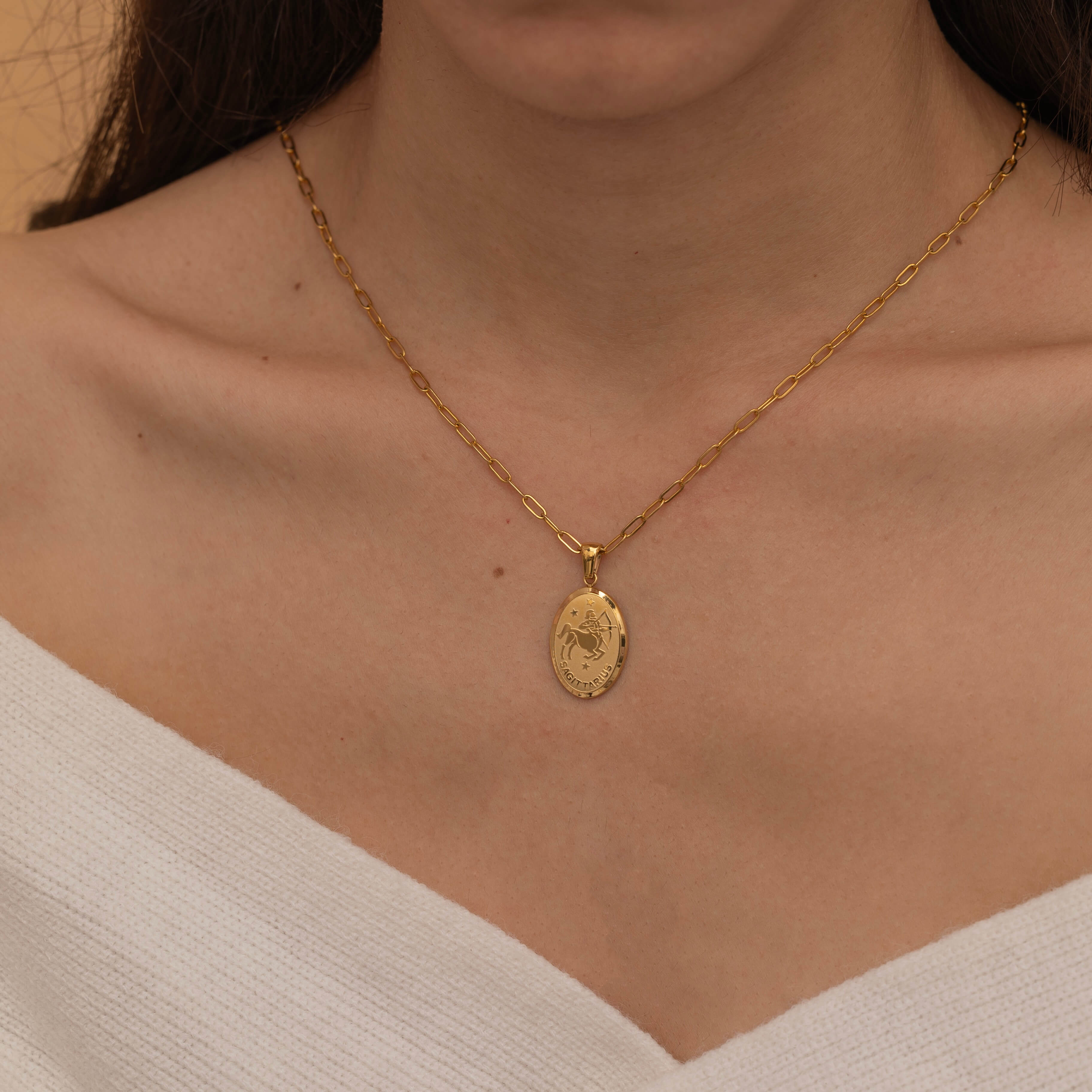 Gold zodiac pendant necklace on a dainty elongated link chain, featuring an engraved oval charm available in all zodiac signs for personalized style.