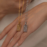 Gold and silver rectangular pendants with tiger engravings, featuring a sparkling cubic zirconia accent. They symbolize the strength tarot necklace. Available in both gold-plated and sterling silver chains.