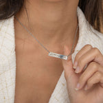 Close-up of a silver bar necklace engraved with a personalized Morse code message, worn by a woman.