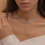 Elegant silver tennis necklace with a continuous row of sparkling, rectangular-cut stones. Perfectly aligned gemstones create a seamless shimmer, adding timeless sophistication to any look. Classic luxury jewelry piece ideal for formal occasions or adding everyday elegance.