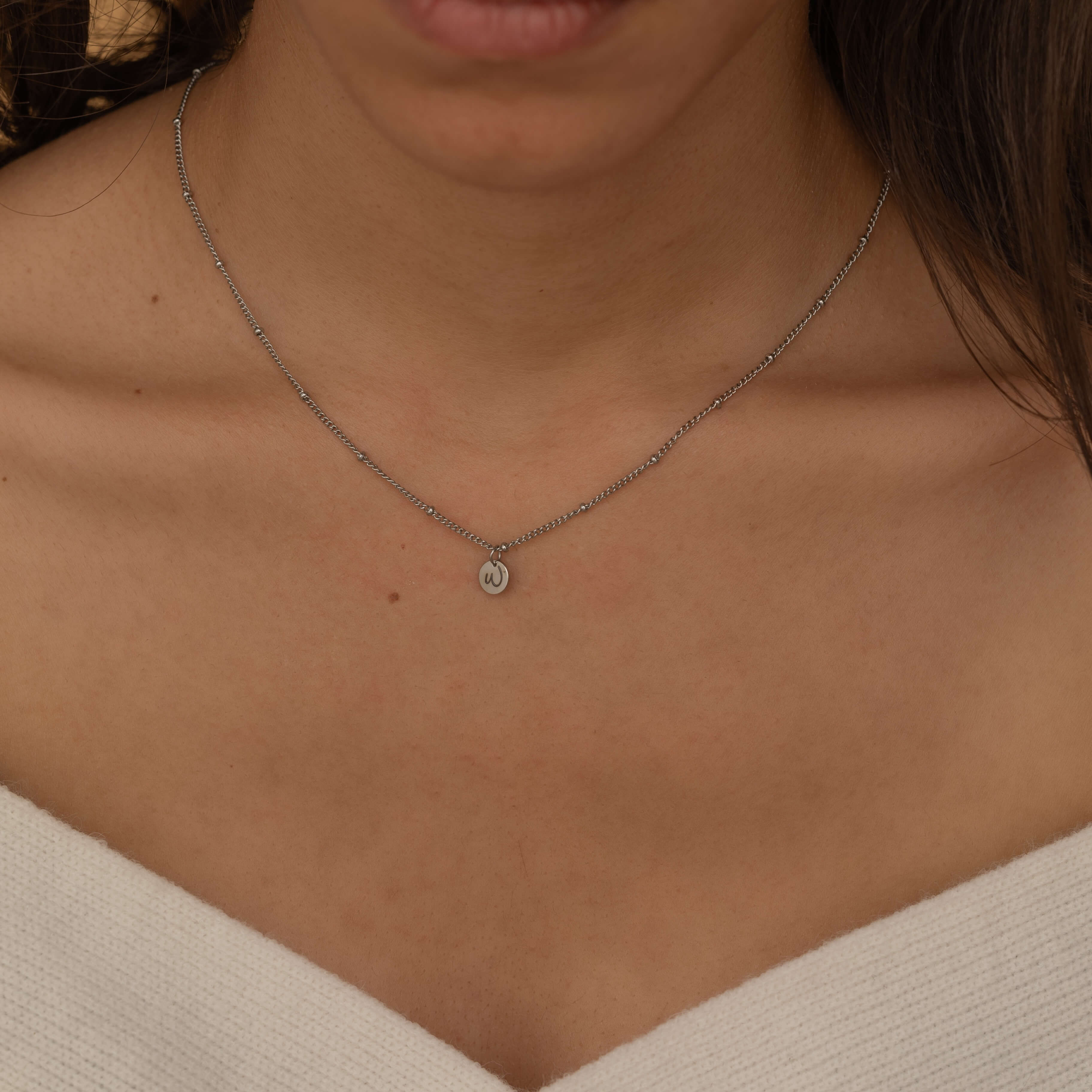 custom initial charm necklaces in gold, silver, and rose gold finishes, each with distinct chain styles and personalized round charms on a marble surface.