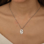 Up-close view of a silver personalized birth flower necklace engraved, worn by a woman.