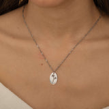Up-close view of a silver personalized birth flower necklace engraved, worn by a woman.