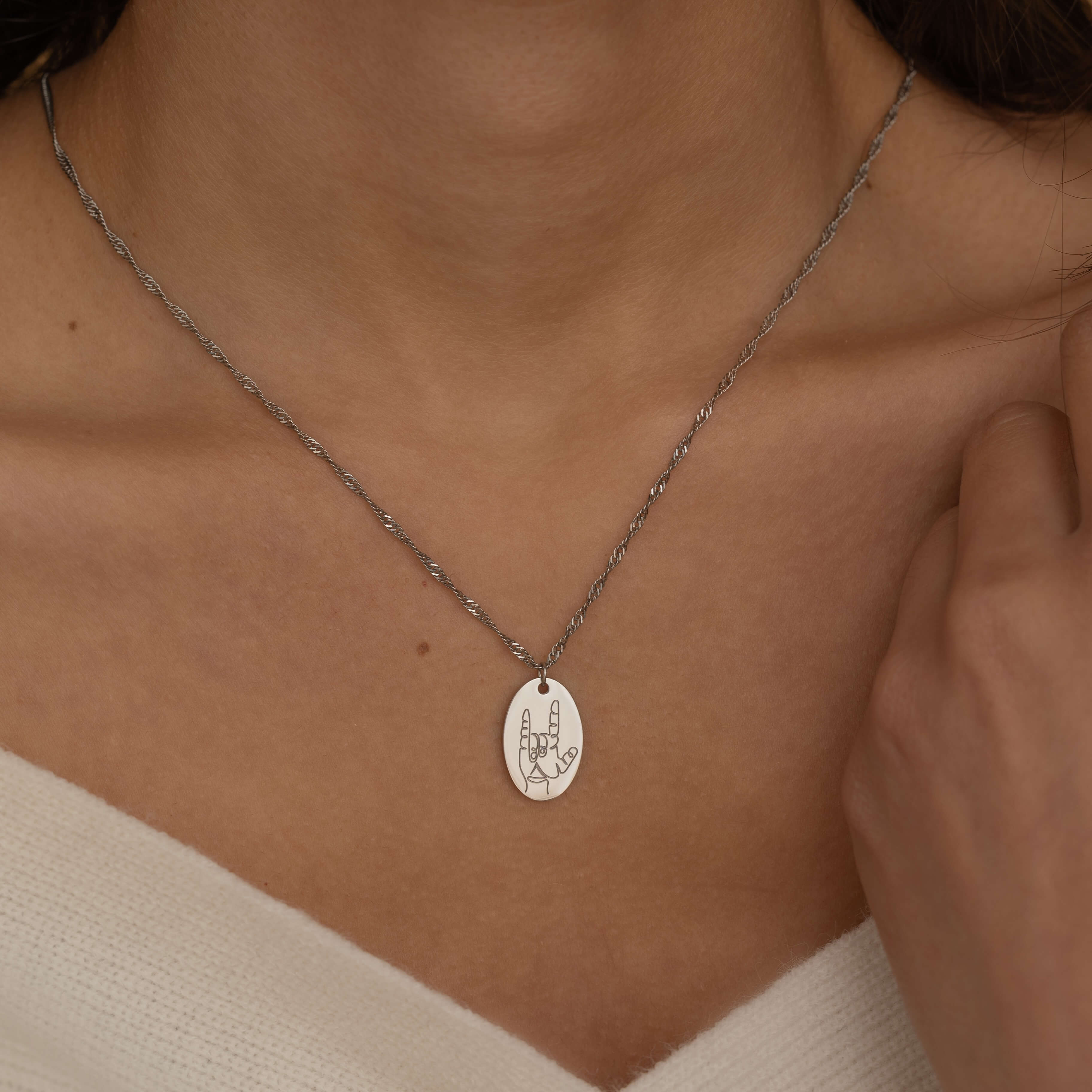 Silver hand gesture necklace. Up close of rocker hand sign engraving 