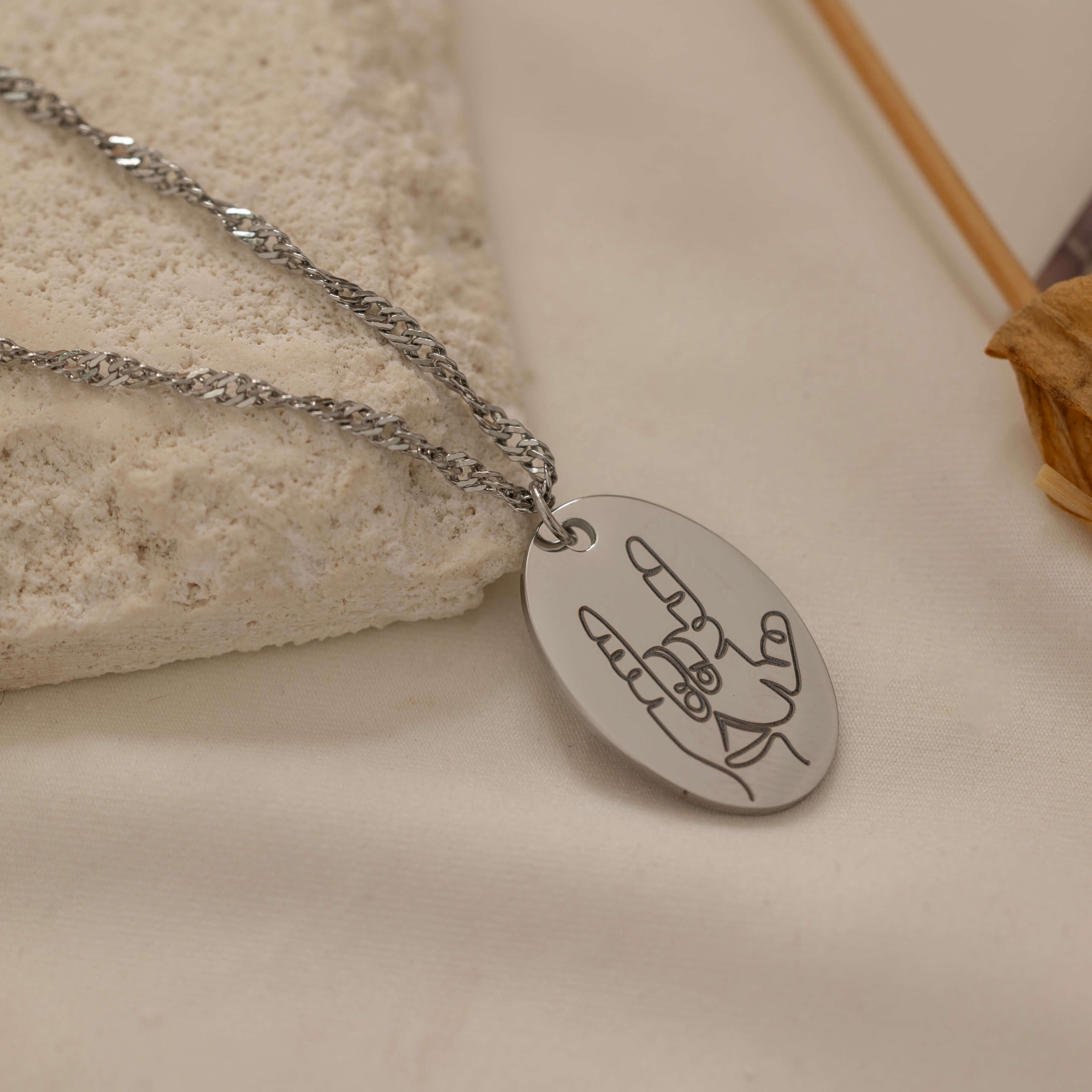 close up of a rocker hand gesture silver necklace.