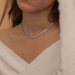 Elegant silver tennis necklace with a continuous row of sparkling, rectangular-cut stones. Perfectly aligned gemstones create a seamless shimmer, adding timeless sophistication to any look. Classic luxury jewelry piece ideal for formal occasions or adding everyday elegance.