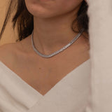 Elegant silver tennis necklace with a continuous row of sparkling, rectangular-cut stones. Perfectly aligned gemstones create a seamless shimmer, adding timeless sophistication to any look. Classic luxury jewelry piece ideal for formal occasions or adding everyday elegance.