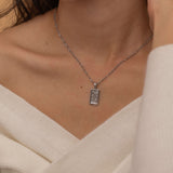 Gold and silver rectangular pendants with tiger engravings, featuring a sparkling cubic zirconia accent. They symbolize the strength tarot necklace. Available in both gold-plated and sterling silver chains.