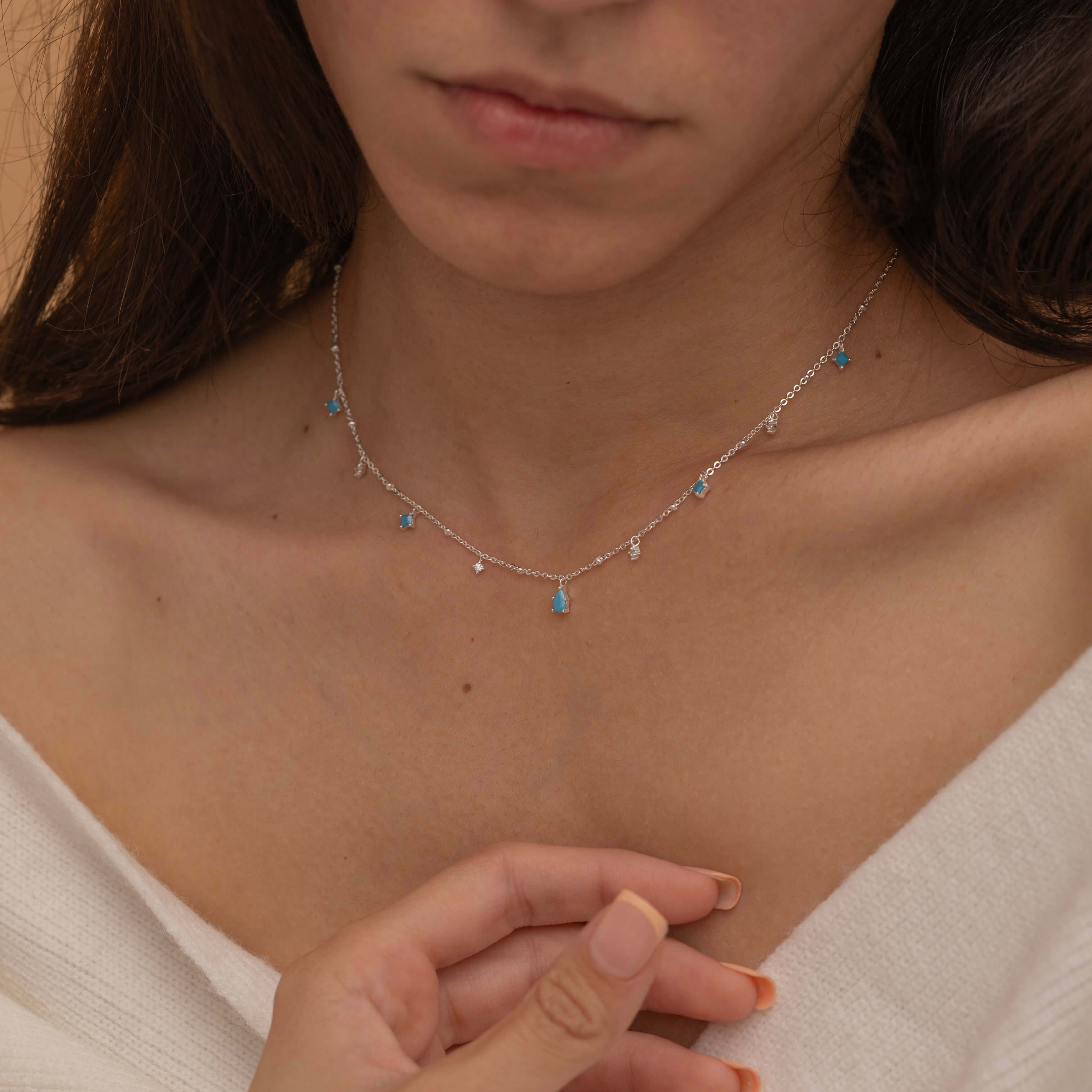 Dainty sterling silver necklace featuring four square turquoise birthstone stones, one centered teardrop-shaped turquoise stone, and four white cubic zirconia accents between the turquoise stones. Perfect for mother’s day and prom. 