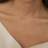 Dainty sterling silver necklace featuring four square blue zircon stones, one centered teardrop-shaped blue zircon stone, and four white cubic zirconia accents between the December birthstones.