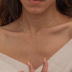 Dainty sterling silver necklace featuring four square pearl birthstone stones, one centered teardrop-shaped pearl stone, and four white cubic zirconia accents between the pearl birthstones. Perfect for mother’s day and prom. 