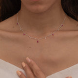 Dainty sterling silver necklace featuring four square pink ruby-colored cubic zirconia stones, one centered teardrop-shaped pink ruby stone, and four white cubic zirconia accents between the pink ruby. 