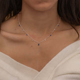 Dainty sterling silver necklace featuring four square sapphire-colored cubic zirconia stones, one centered teardrop-shaped sapphire stone, and four white cubic zirconia accents between the sapphire.