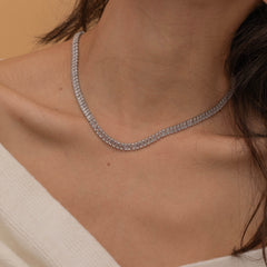 Elegant silver tennis necklace with a continuous row of sparkling, rectangular-cut stones. Perfectly aligned gemstones create a seamless shimmer, adding timeless sophistication to any look. Classic luxury jewelry piece ideal for formal occasions or adding everyday elegance.