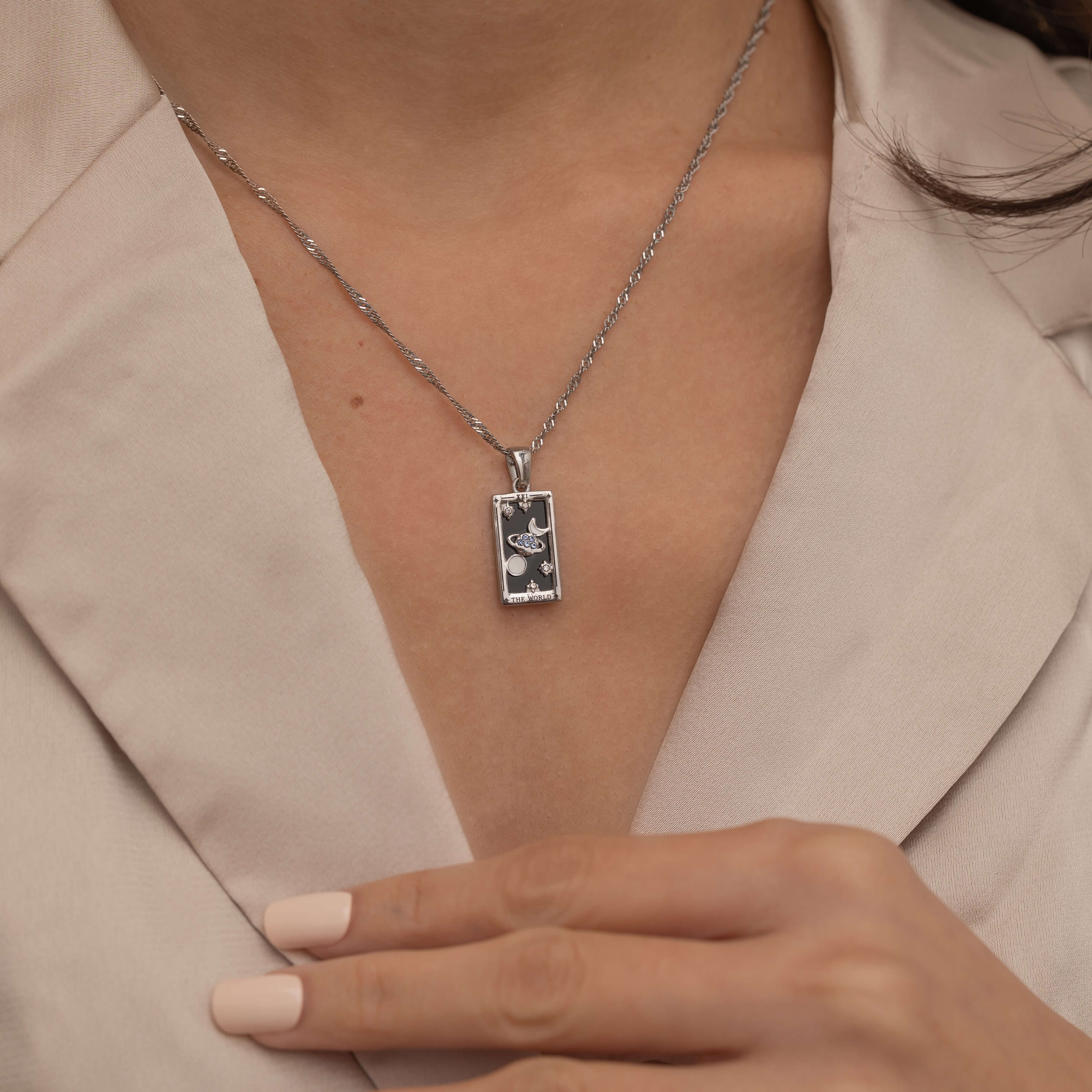 Silver the world tarot necklace with cubic zirconia accents and an black onyx back stone, symbolizing completion, unity, and the cyclical nature of life