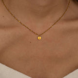 Three custom initial charm necklaces in gold, silver, and rose gold finishes, each with distinct chain styles and personalized round charms on a marble surface.