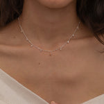 Dainty sterling silver necklace featuring four square champagne topaz-colored cubic zirconia stones, one centered teardrop-shaped champagne topaz stone, and four white cubic zirconia accents between the champagne topaz. 