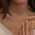 Dainty sterling silver necklace featuring four square turquoise birthstone stones, one centered teardrop-shaped turquoise stone, and four white cubic zirconia accents between the turquoise stones. Perfect for mother’s day and prom. 